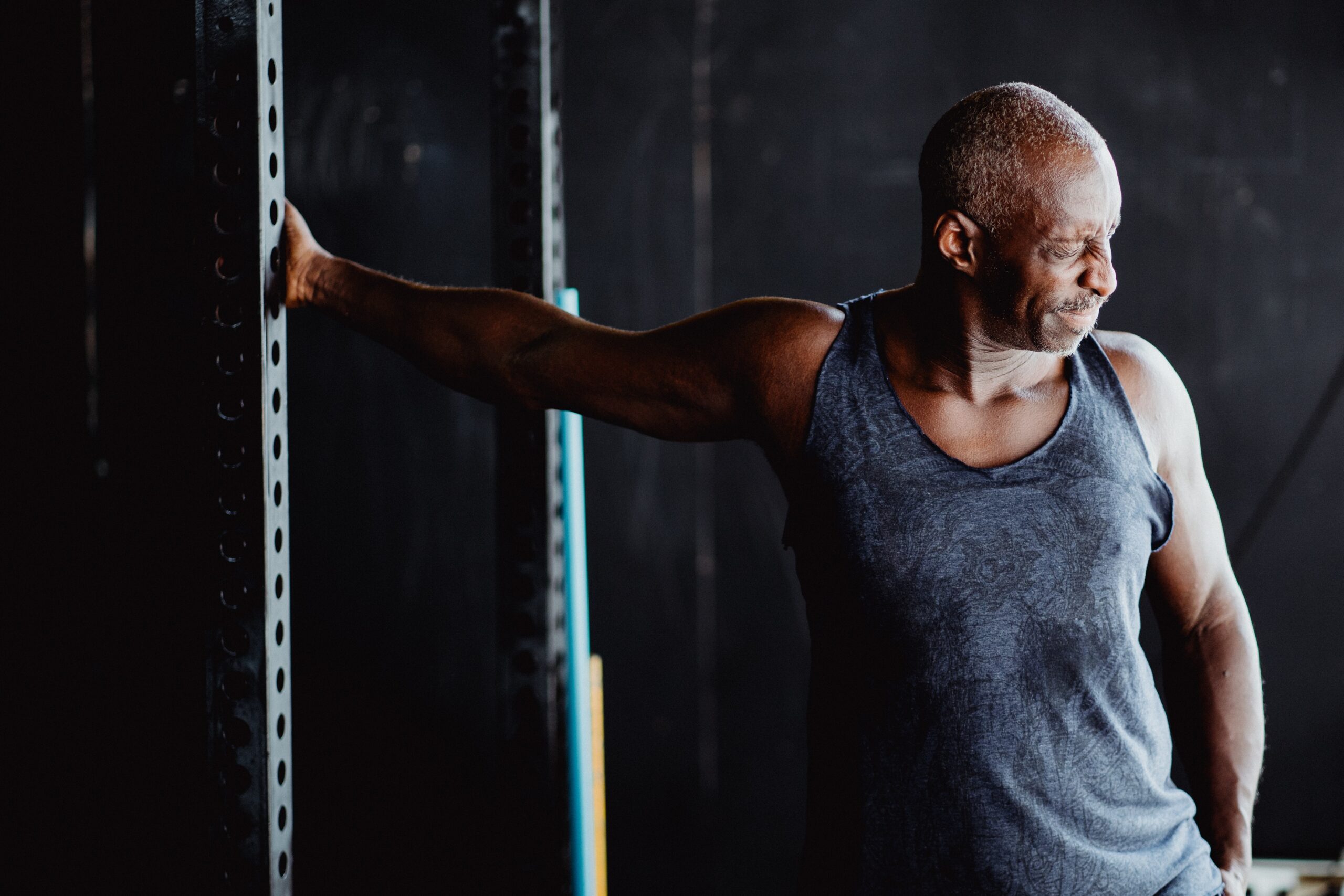 older man stretching shoulder at the gym