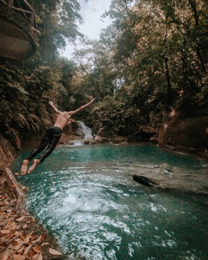 man diving into scenic natural pool
