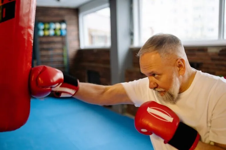 older man punching boxing bag